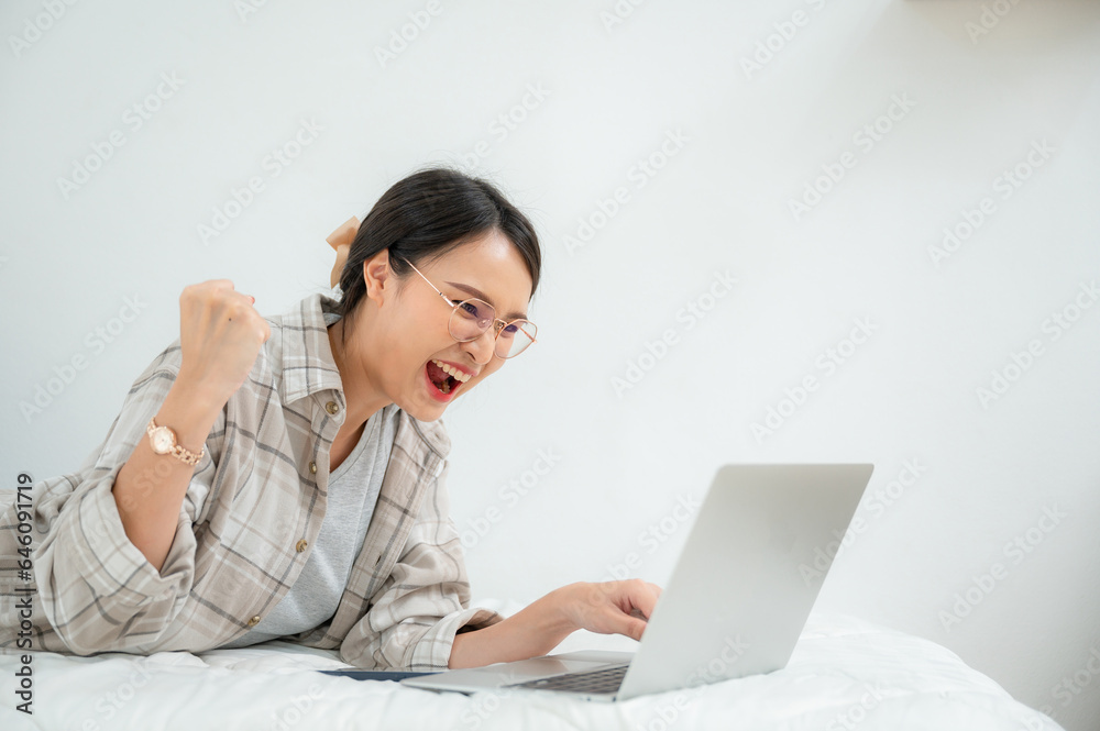 A happy freelance asian woman working at home feeling excited and very happy with laptop. A happy freelance asian woman working at home feeling excited and very happy with laptop.