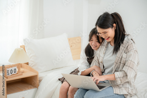 Asian schoolgirl with mother using laptop computer studying online at home Happy students with education looking at PC screen Watch the webinar online course homework