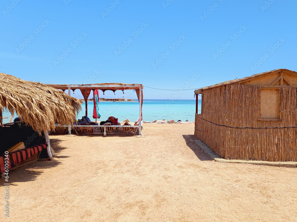 Bedouin huts on the beach with turquoise water of the Sinai Peninsula. Beach bars and Arab chill out. Constructions and Architecture of the desert. Extreme landscapes and living conditions.