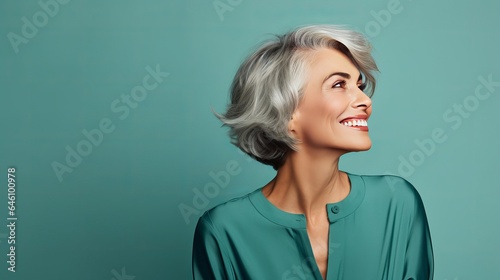 Picture of a mature, happy, pretty woman having fun in a club, taken from the side, isolated on a turquoise background.