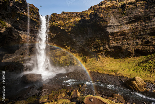 Scenic view of the picturesque Kvernufoss waterfall in spring, with a rainbow in the foreground, near Route 1 / Ring Road, Southern Region, Iceland