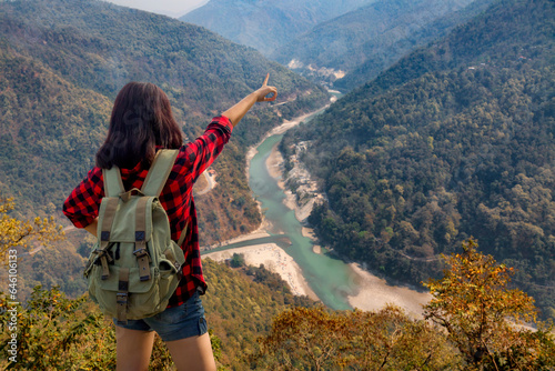 Young girl tourist enjoys a scenic aerial view of Teesta river and Himalayan landscape from Lover's Point at Darjeeling, India.