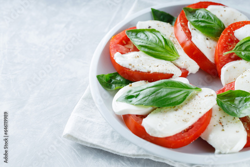 Salad Caprese with tomato, mozzarella and basil on gray background. Top view. Copy space