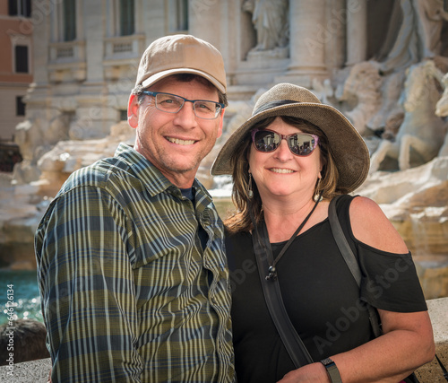 Smiling caucasian tourist couple on holiday in Rome in front of Trevi fountain