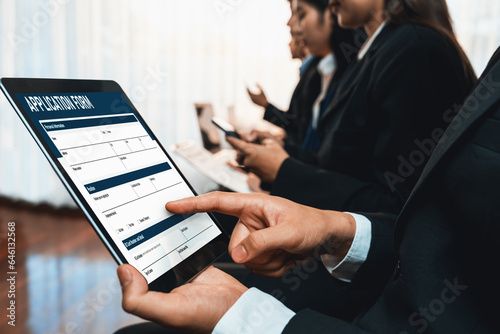 Canvas Print Job applicant sitting in waiting room for job interview with other candidates while applying on job application form with laptop in corporate company