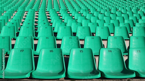 fragment of a stadium tribune with rows of green plastic chairs without people, like a city background, unoccupied seats for fans in the sector for watching sports competitions, city infrastructure photo