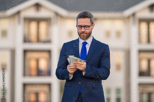 Business man in suit holding cash money in dollar banknotes outdoor. Portrait of business man with bunch of dollar. Dollar money concept. Career wealth business. Insurance agent. Success business.