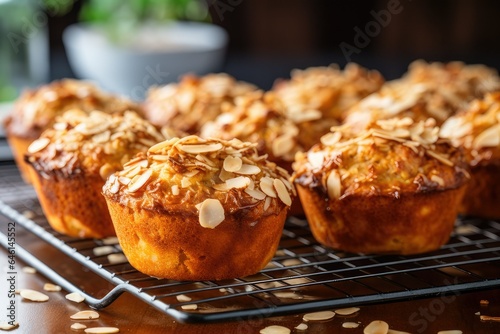 A tray of freshly baked oatmeal muffins, cooling on a wire rack. The muffins are golden brown and fluffy, with a moist and flavorful center. They are topped with a generous amount of crunchy oats 