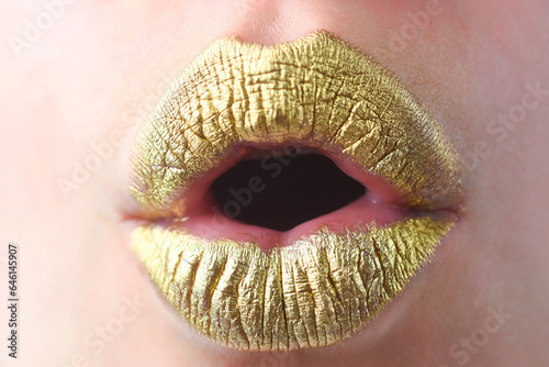 Surprised mouth. Close up woma face with gold lips. Gold paint on mouth. Golden lips. Luxury gold lips make-up. Golden lips with creative metallic lipstick. Gold metal lip. Sensual woman mouth.