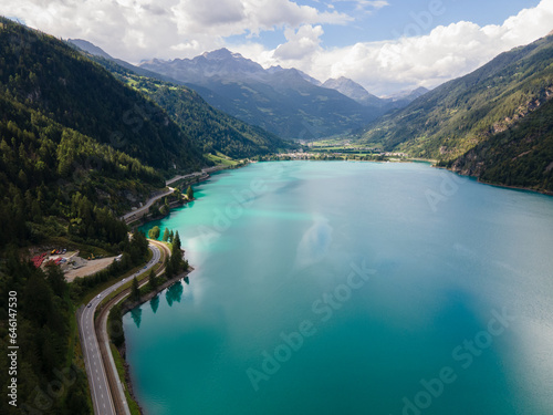 Aerial drone view of Poschiavo alpine lake and road in the Switzerland mountains. Miralago Bernina Express train station. Swiss Alps	