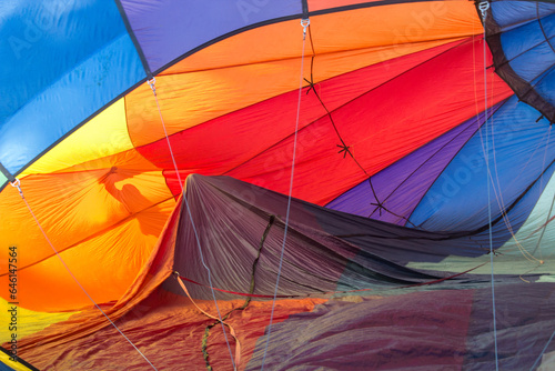 A hot air balloon is being inflated. You can see the interior of the balloon. It is red, orange, blue, brown and purple.