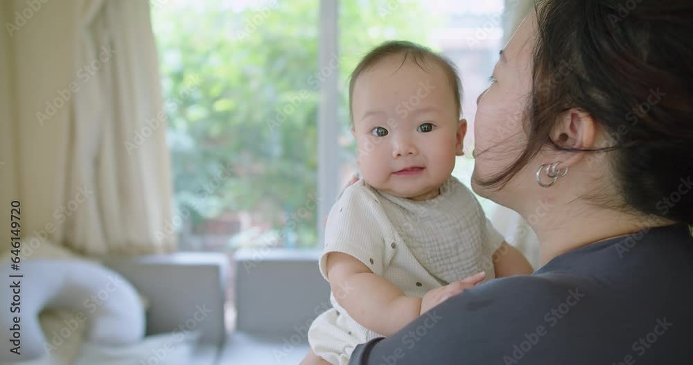 Close up portrait young mother hold in arms hug cuddle little cute baby girl toddler and kiss, loving Asian mom embrace small baby child, relax enjoy tender family moment Motherhood concept