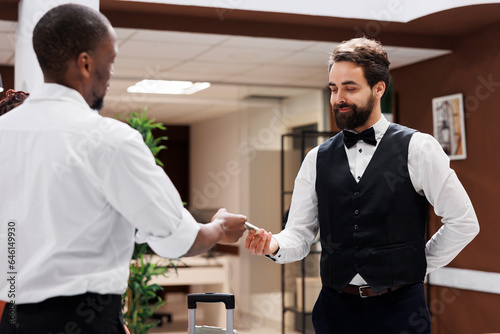 Fotografie Hotel porter taking money from client, accepting to carry luggage and help with bags after check in process