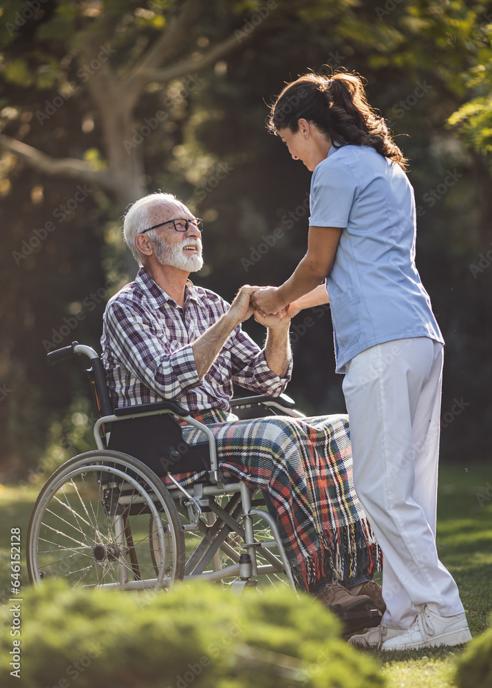 Nurse comforting senior man in wheelchair in park Nurse comforting senior man in wheelchair in park
