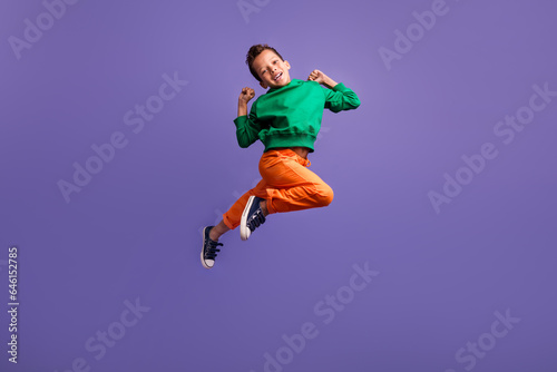 Photo of overjoyed nice boy wear green trendy outfit raise fist have fun enjoy rejoice shopping sale isolated on purple color background © deagreez
