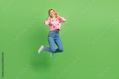 Full length photo of lovely young lady headphones jump dressed stylish pink strawberry print garment isolated on green color background