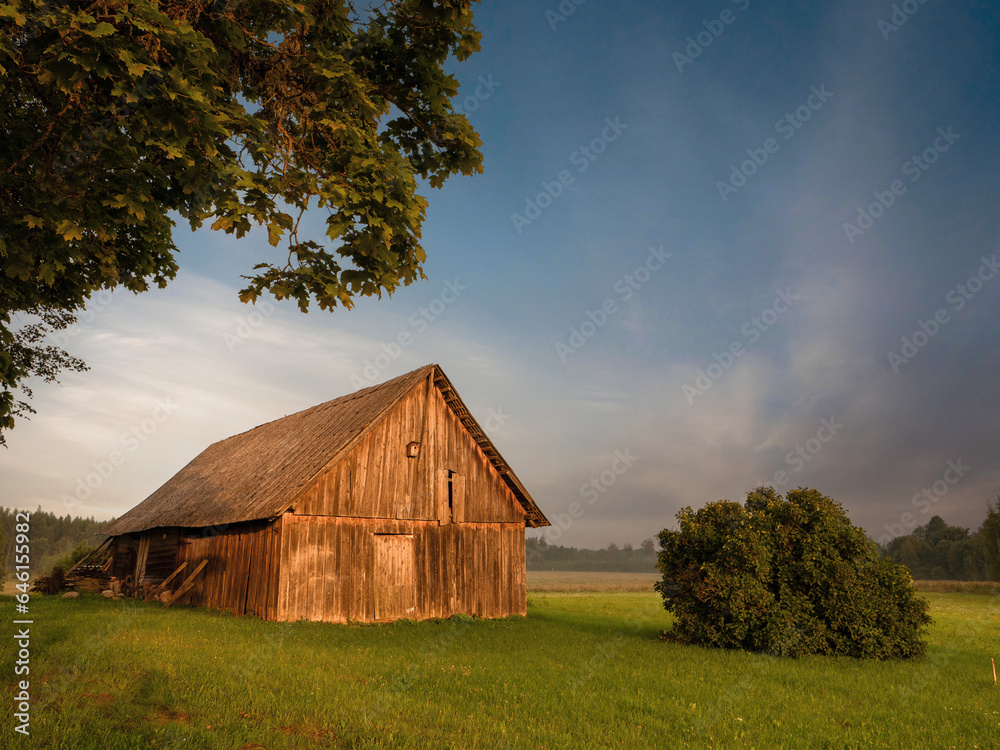 Old wooden barn in country side. Rural area in Latvia. Place for storage made of wood, simple construction local material. Living on a farm. Nobody. Beautiful nature scene. Old wooden barn in country side. Rural area in Latvia. Place for storage made of wood, simple construction local material. Living on a farm. Nobody. Beautiful nature scene.