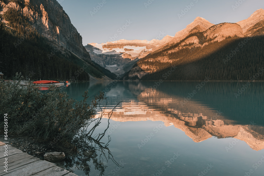 Lake Louise sunrise with red canoe in landscape photo.