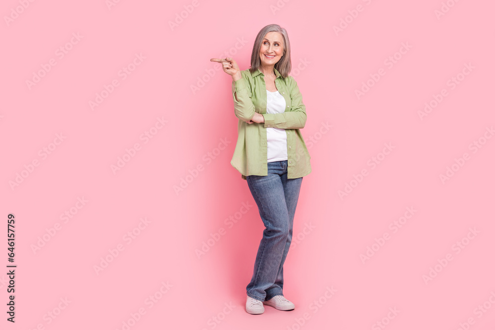 Full length photo of cheerful satisfied lady dressed trendy clothes arm direct empty space buy novelty isolated on pink color background Full length photo of cheerful satisfied lady dressed trendy clothes arm direct empty space buy novelty isolated on pink color background