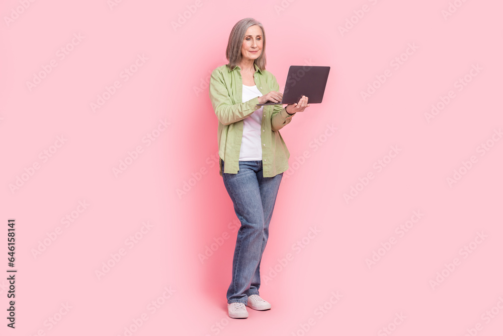 Full length photo of lovely confident retired lady wear stylish clothes chatting social media isolated on pink color background Full length photo of lovely confident retired lady wear stylish clothes chatting social media isolated on pink color background