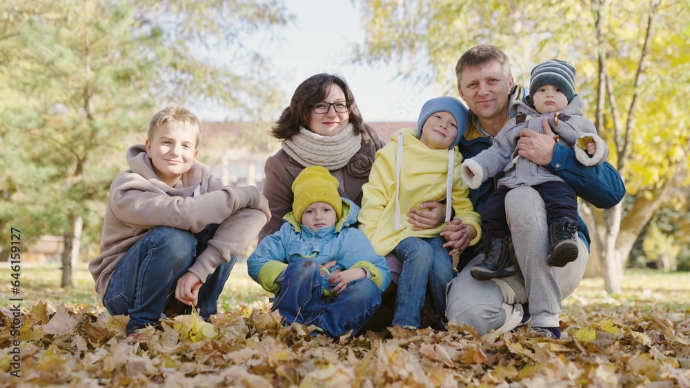 Family vacation, weekend, Big happy family, parents and children walk in park in autumn. Dad son, mom children play together on yellow leaves of city autumn park. Family walk with children outdoors