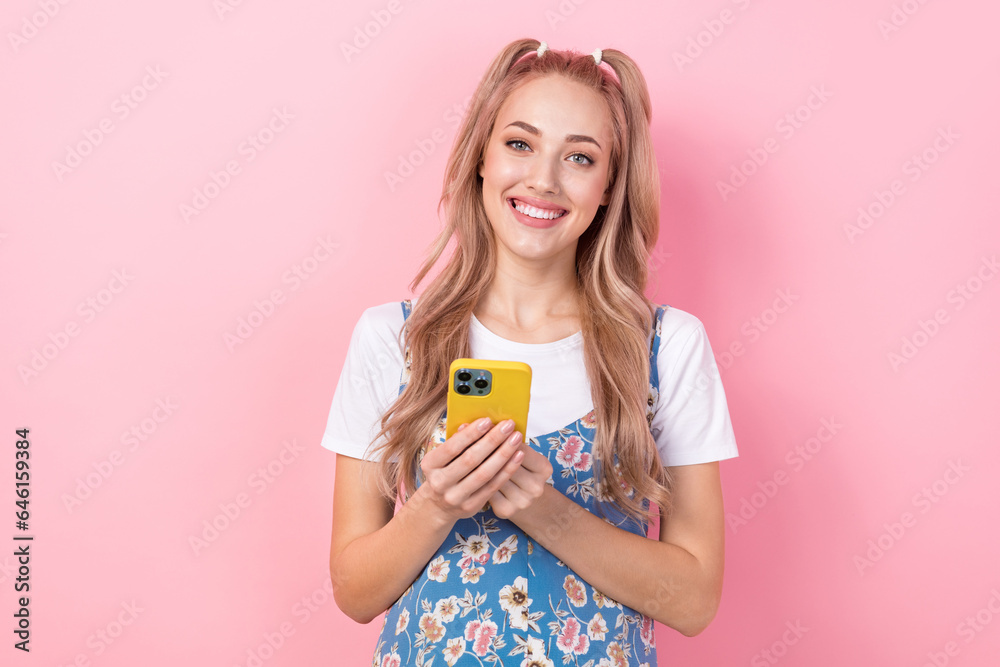 Photo portrait of lovely young lady holding device typing dressed stylish flower print garment isolated on pink color background Photo portrait of lovely young lady holding device typing dressed stylish flower print garment isolated on pink color background