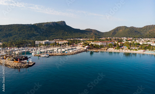 Picturesque summer aerial view of coastal area of Kemer and marina with moored yachts on Mediterranean coast on background of Taurus Mountain range, Antalya province. Famous resort on Turkish Riviera