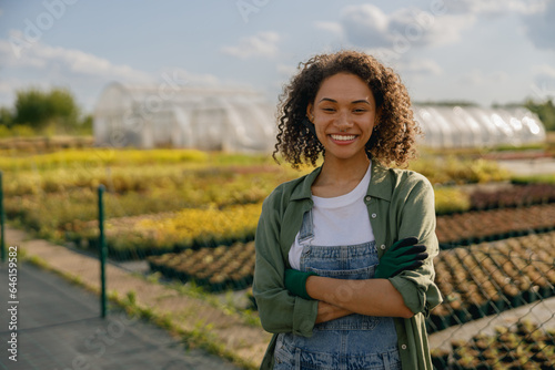 Smiling female agronomist standing on the field on greenhouses background. High quality photo photo