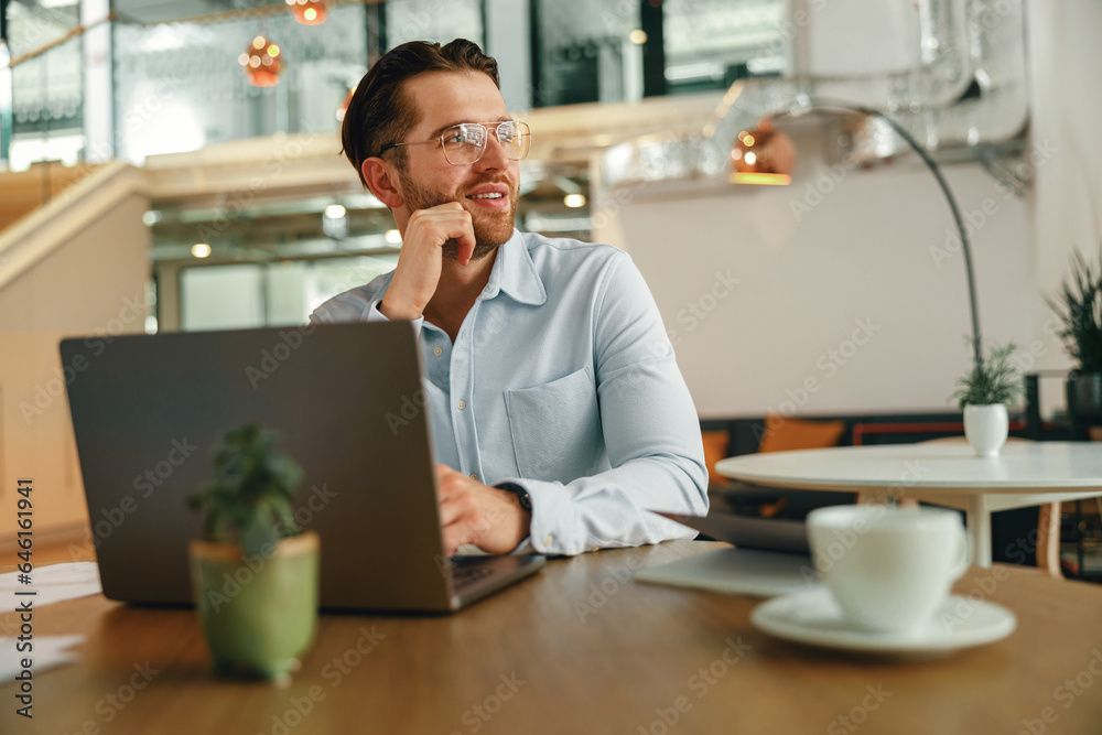 Smiling male manager drinking coffee during working on laptop in modern office . High quality photo Smiling male manager drinking coffee during working on laptop in modern office . High quality photo