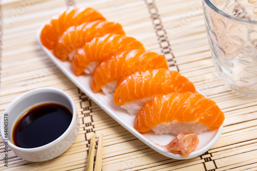 Sake nigiri - tasty dietary sushi with salmon and tuna, soy sauce closeup