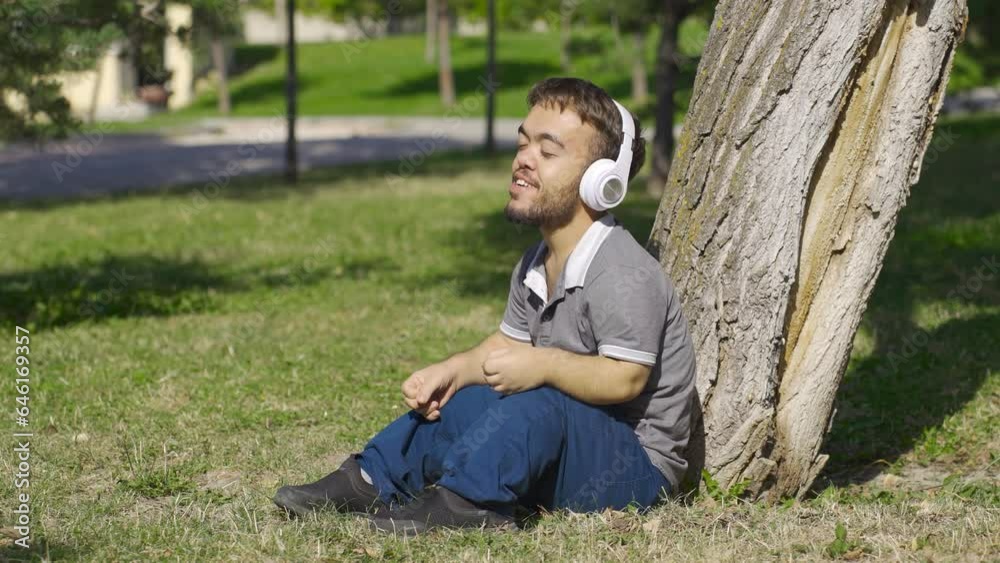 Dwarf young man sitting on the floor with joy listens to music. Dwarf young man sitting on the floor with joy listens to music.
