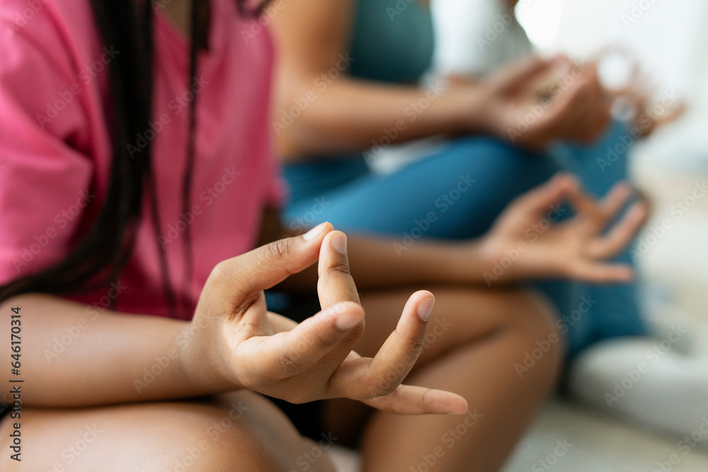 African American girl doing yoga, sitting in lotus pose, holding hands, selective focus on hands