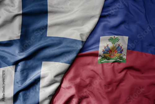 big waving national colorful flag of finland and national flag of haiti .