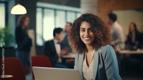 Beautiful Middle Eastern Manager Sitting at a Desk in Creative Office. Young Stylish Female with Curly Hair Using Laptop Computer in Marketing Agency. Colleagues Working in the Backgro : Generative AI