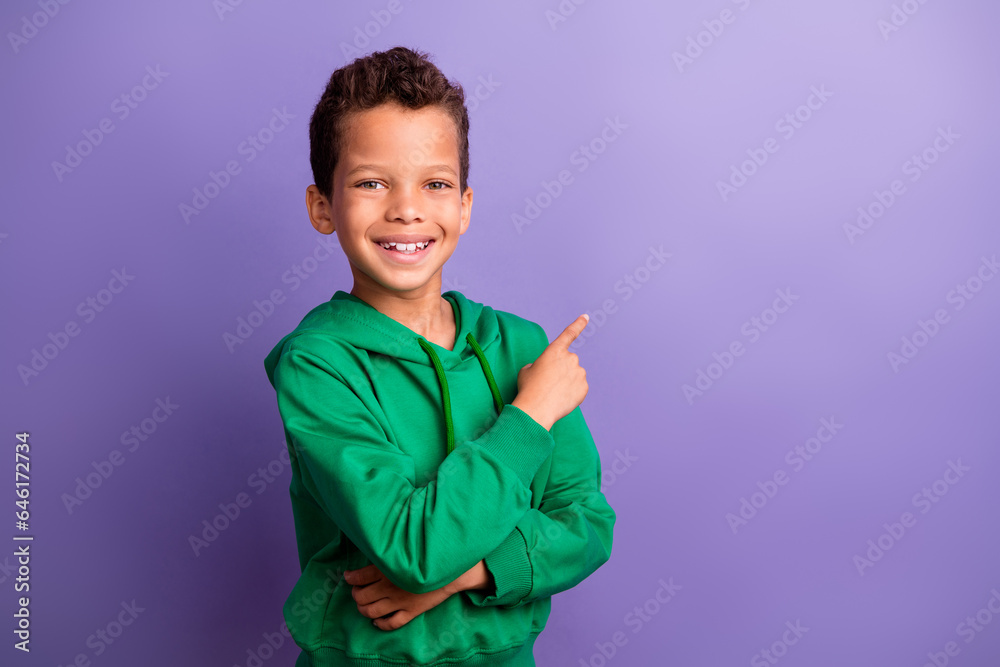 Photo of cool charming small boy wear green sweatshirt showing finger empty space isolated violet color background Photo of cool charming small boy wear green sweatshirt showing finger empty space isolated violet color background
