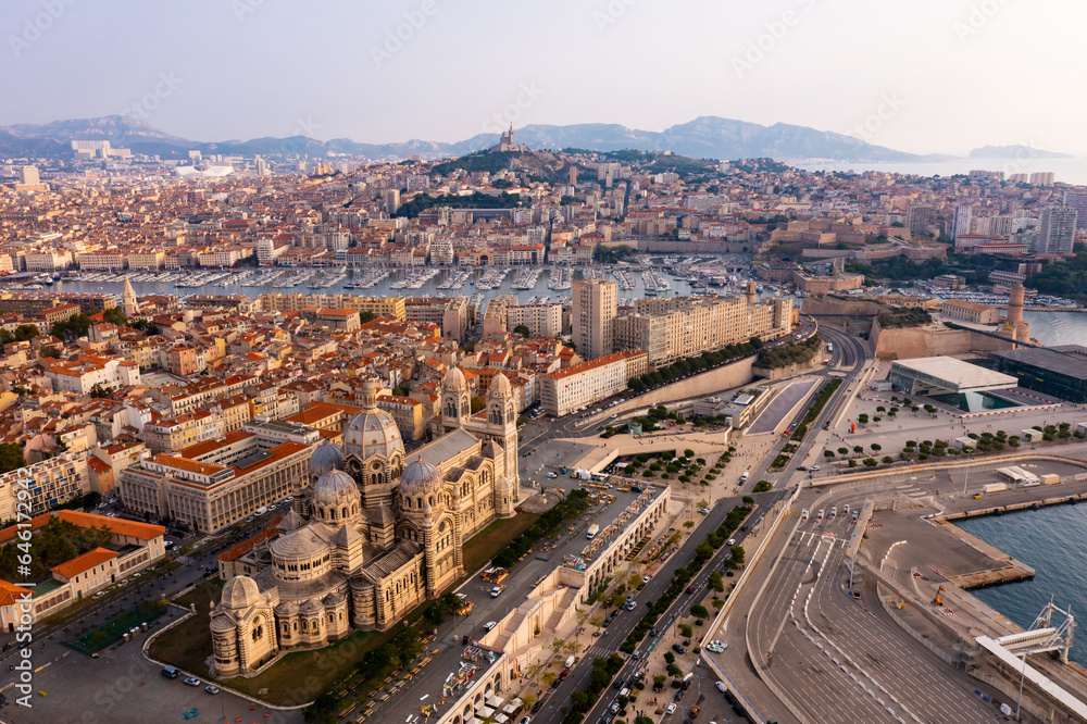 Scenic drone view of Marseille cityscape on Mediterranean coast overlooking Romanesque Cathedral of Saint Mary Major, medieval Fort Saint-Jean and Old Port with moored yachts, France