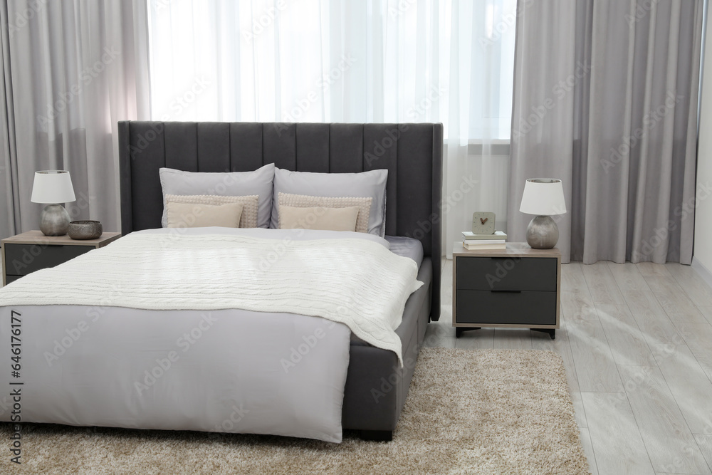 Stylish bedroom in soft light colors with comfortable bed and bedside tables. Interior design