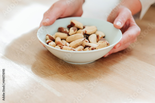 Brazil nuts in the diet. Healthy fats in the diet. Brazil nuts in a white ceramic cup in hand on a wooden table.Nuts and seeds.Useful healthy snack. 