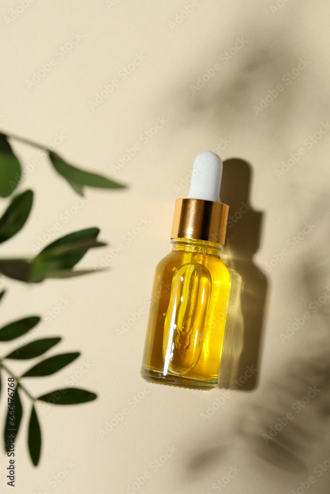 Bottle of cosmetic oil and leaves on beige background, top view Bottle of cosmetic oil and leaves on beige background, top view
