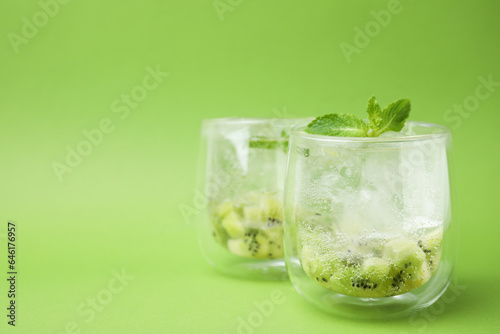 Refreshing drink with kiwi and mint on light green background, closeup. Space for text