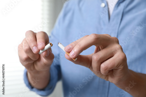 Stop smoking concept. Man holding pieces of broken cigarette indoors  closeup