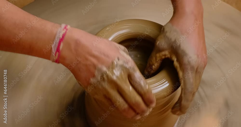 Skilled wet hands of potter shaping the clay on potter wheel and sculpting vase. Manufacturing traditional handmade Indian bowl, jar, pot, jug. Shilpagram, Udaipur, Rajasthan, India, Asia Skilled wet hands of potter shaping the clay on potter wheel and sculpting vase. Manufacturing traditional handmade Indian bowl, jar, pot, jug. Shilpagram, Udaipur, Rajasthan, India, Asia