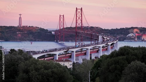 View of Lisbon from Miradouro do Bairro do Alvito tourist viewpoint with Tagus river, traffic on 25th of April Bridge, and Christ the King statue at sunset. Lisbon, Portugal, Europe photo