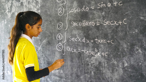 Happy Rural School Girl wearing School Uniform Standing in Front of A Black Board.