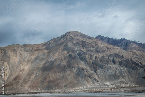 Scenic view of Himalayas and Ladakh ranges. Beautiful barren hills in Ladakh with dramatic clouds in the background. View from the road from Nubra Valley to Turuk. Siachen area in Leh Ladakh.