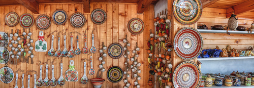 tourist shop in Bulgaria with ceramics and pottery plates, spoons, garlic, on a wooden pine wall