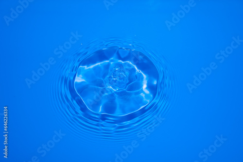 Close up image of water droplets falling into blue water