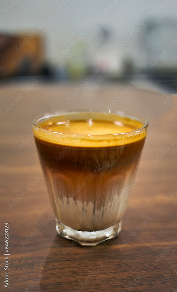 High angle view a glass of Dirty Coffee on wooden table, espresso shot over cold fresh milk created gradient layer called dirty, cold beverage menu in cafe or coffee shop High angle view a glass of Dirty Coffee on wooden table, espresso shot over cold fresh milk created gradient layer called dirty, cold beverage menu in cafe or coffee shop