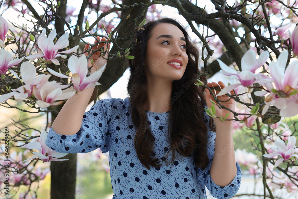 Beautiful woman near blossoming magnolia tree on spring day