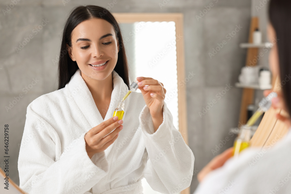 Young woman with cosmetic serum in her hands in bathroom Young woman with cosmetic serum in her hands in bathroom